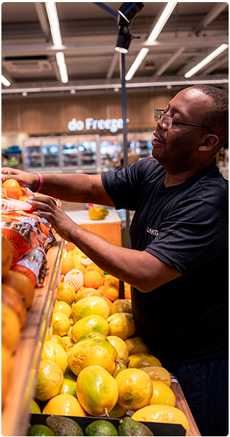 Supermercado - homem arrumando gôndolas de hortifruit em supermecado